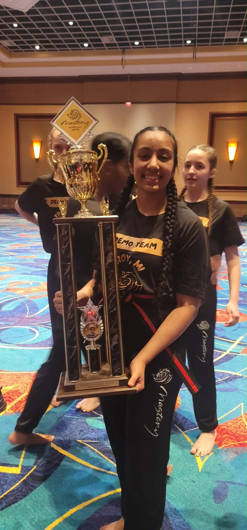 Mastery Troy Demo Team member proudly holding the Night of Champions 1st place trophy