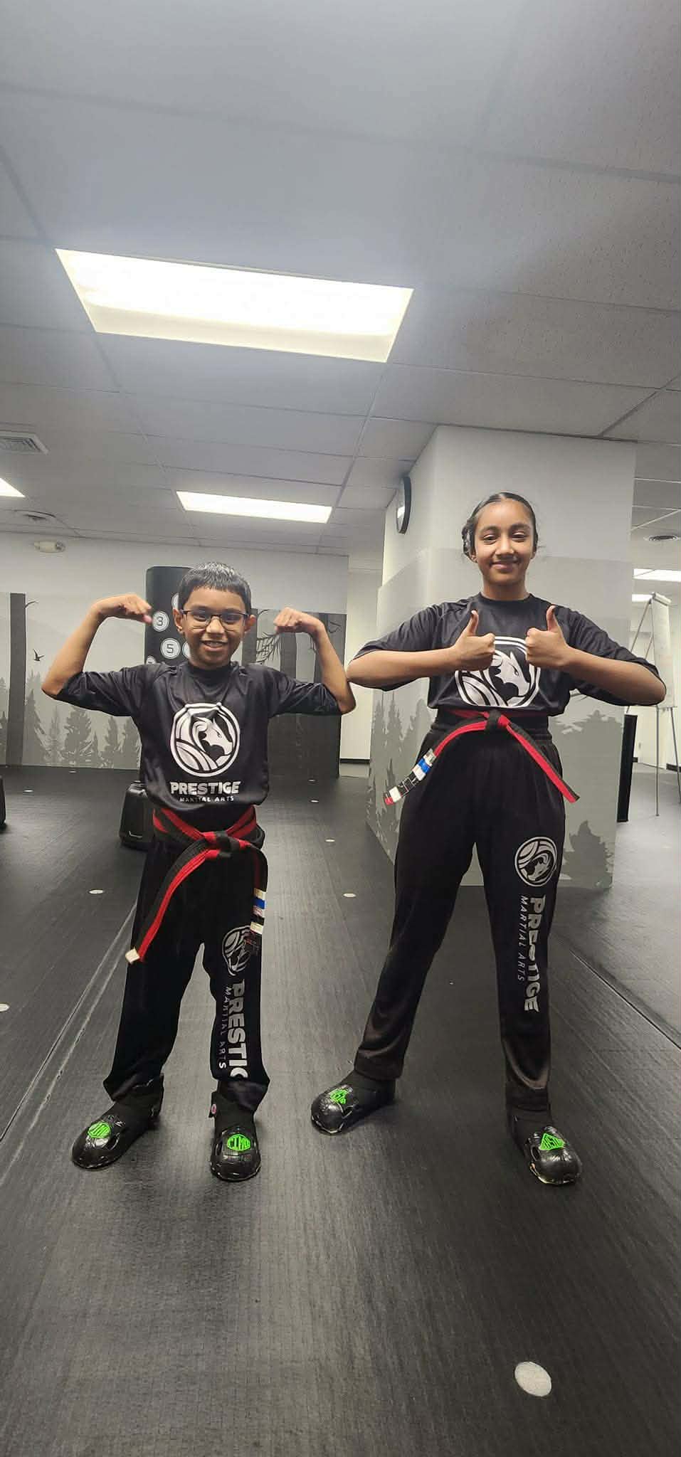 Nishi Bergi and her brother posing confidently in their Prestige Martial Arts uniforms with red belts