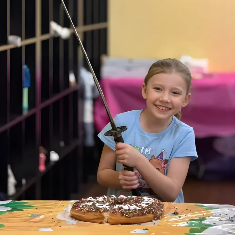 Birthday child cutting the cake with a samurai sword at a Mastery kids birthday party in Troy MI