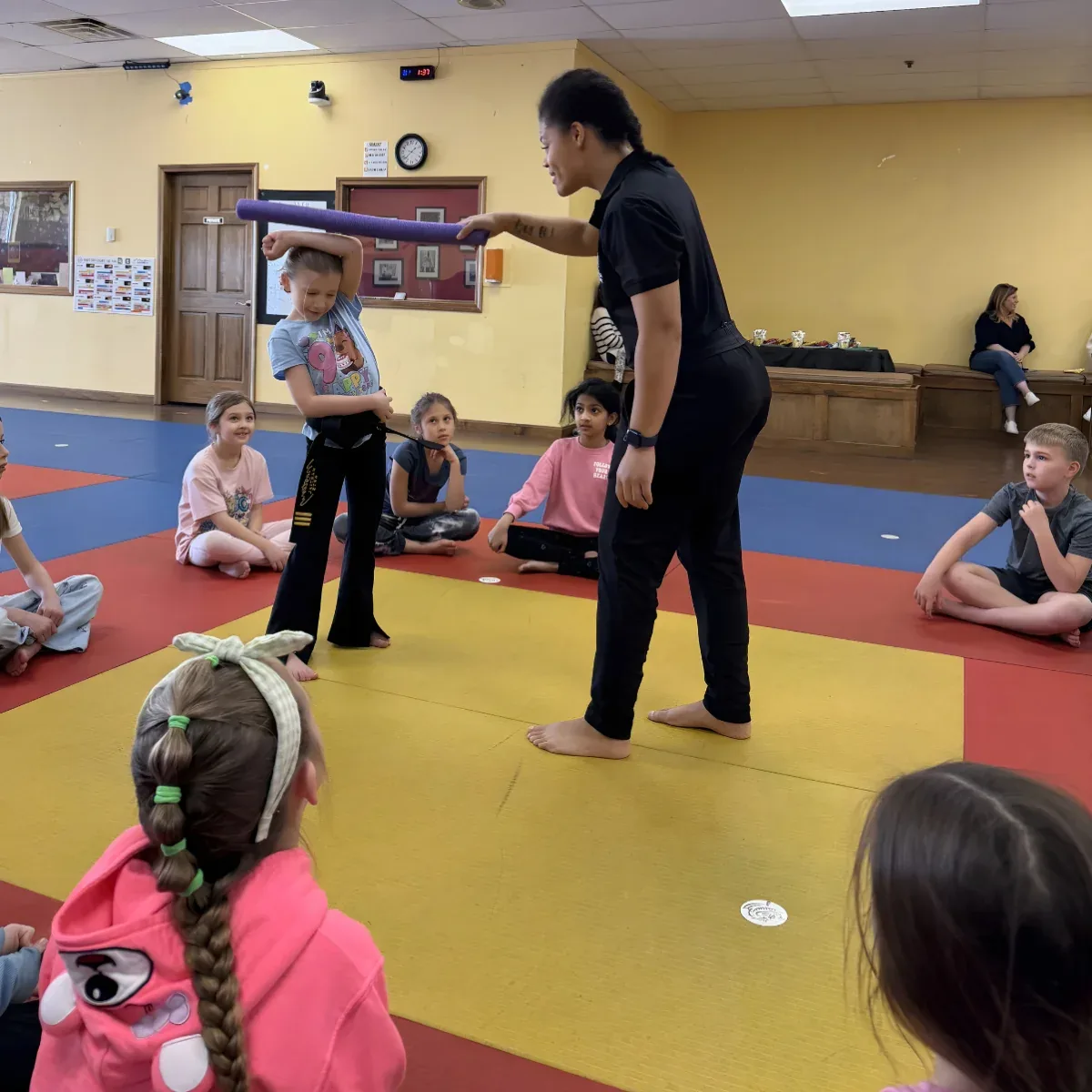 Mastery instructor holding a breaking board for the birthday child while the guests watch