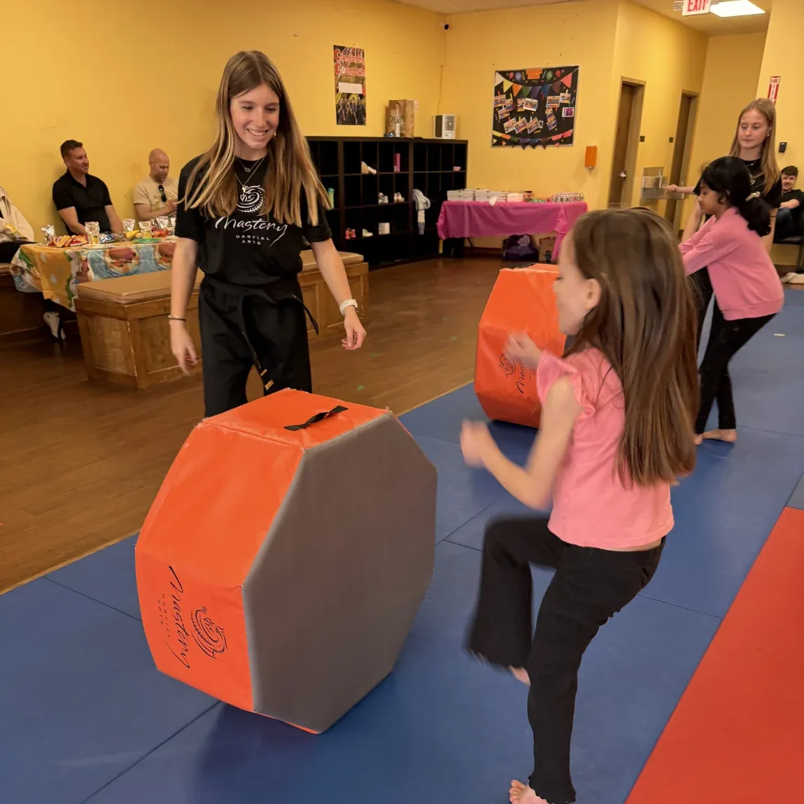 Mastery instructor leading birthday guests through a kicking activity on the mats