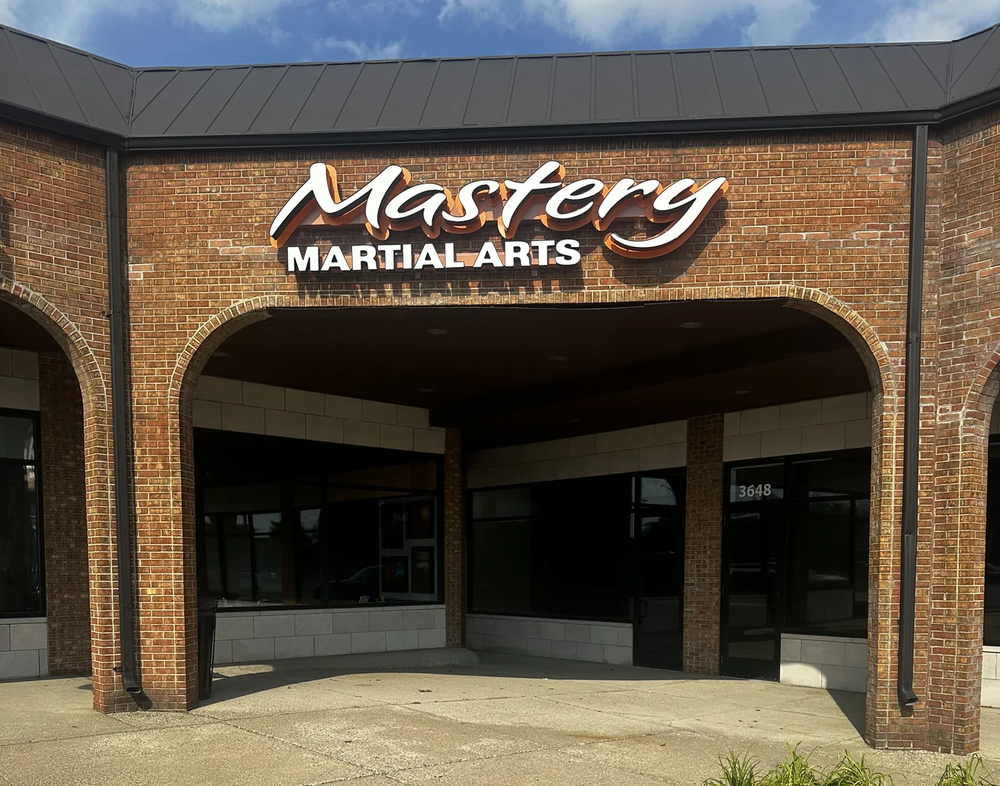 Our Troy School | Mastery Martial Arts Troy MI 3 The Mastery Martial Arts storefront on Rochester Road in Troy MI, with the lit sign above the brick archway